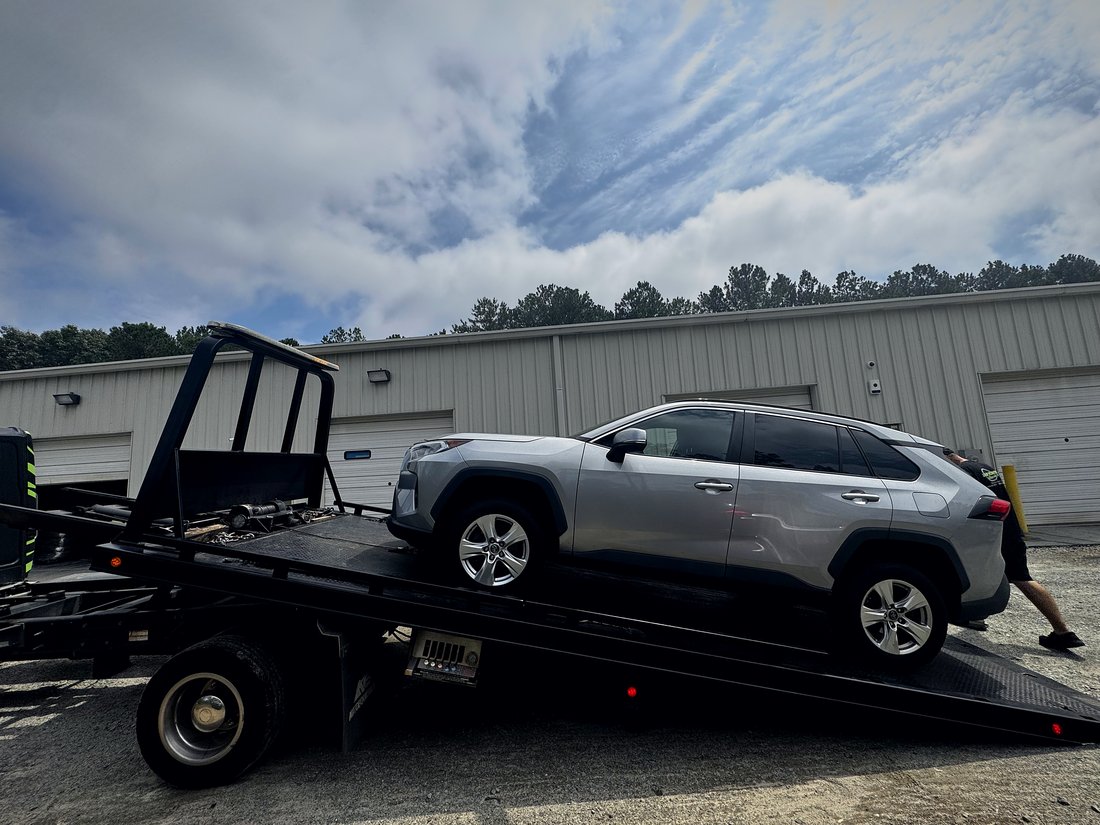 An SUV being winched onto the tilted rollback deck